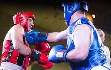 Charity boxing match in progress, two boxers in red and blue headgear