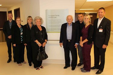 Group beside the dedication plaque for the Paruggia Family Medical Unit