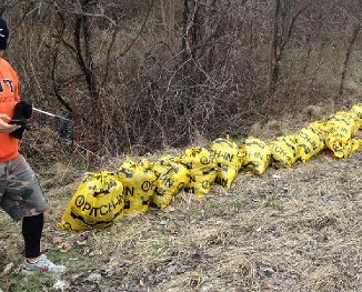 Volunteer collecting filled Pitch-In cleanup bags along a hillside
