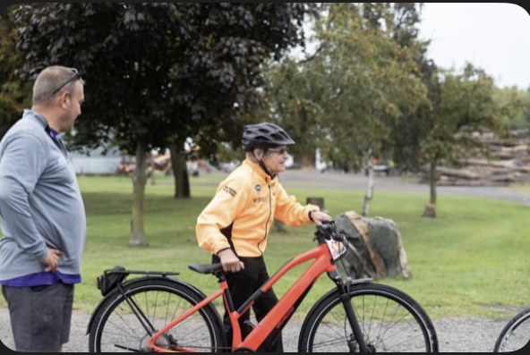 A cyclist in a yellow jacket and helmet with his bicycle at the Big Move Cancer Ride